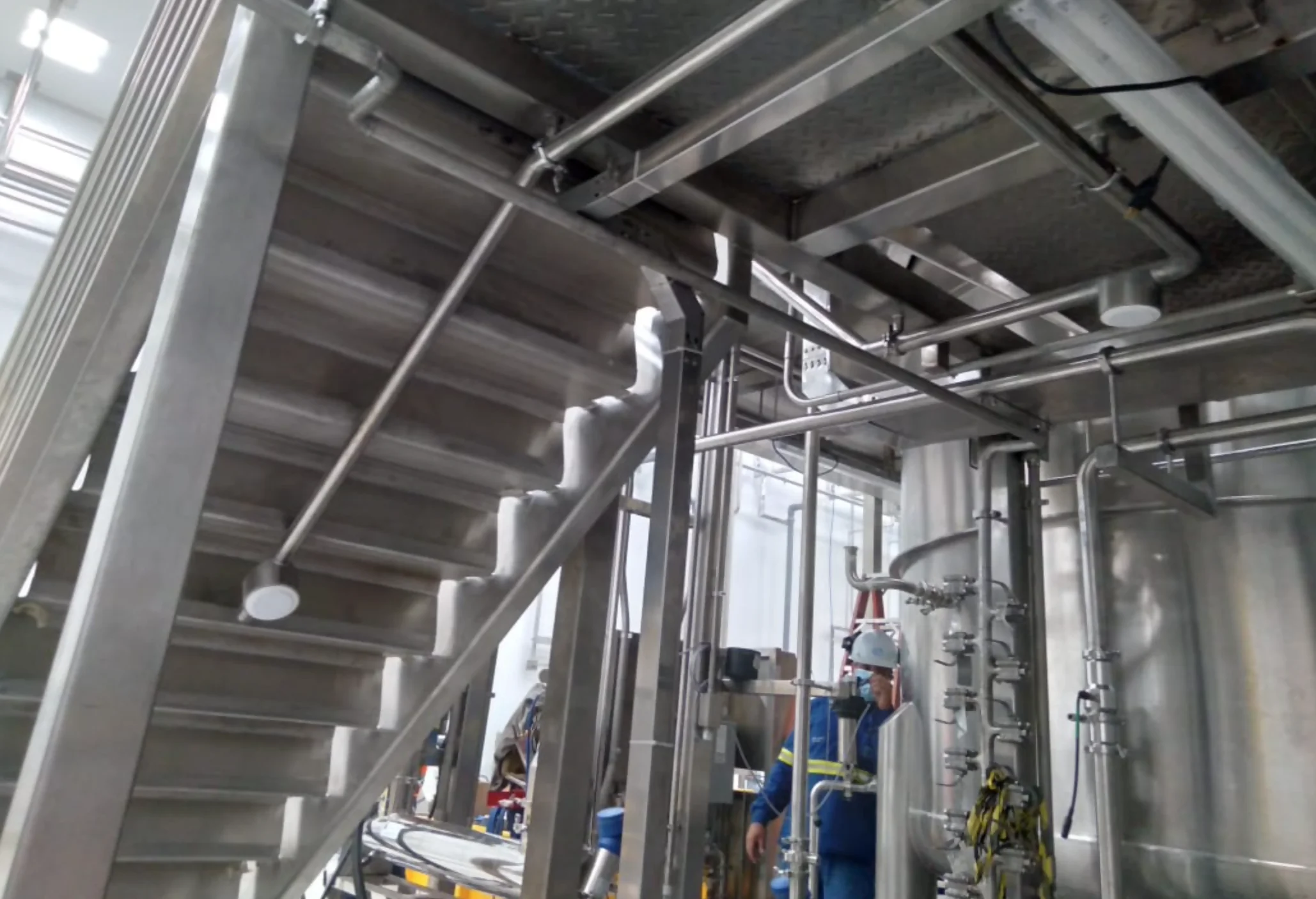 Tubulações em aço inox da HPR instaladas sob escada em ambiente industrial